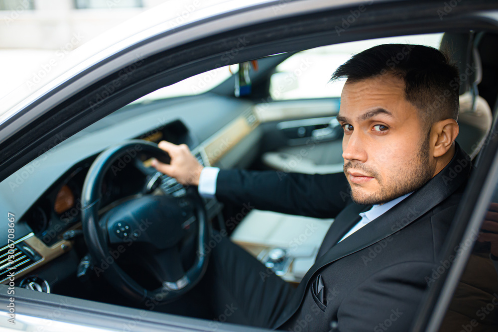 young bearded male behind wheel in his executive car, driving car