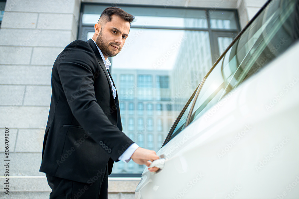 handsome caucasian businessman opening door of white executive car, wearing tuxedo formal wear handsome caucasian businessman opening door of white executive car, wearing tuxedo formal wear