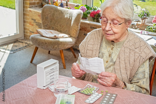 Elderly Woman Reading a Leaflet, Pills on the Table
