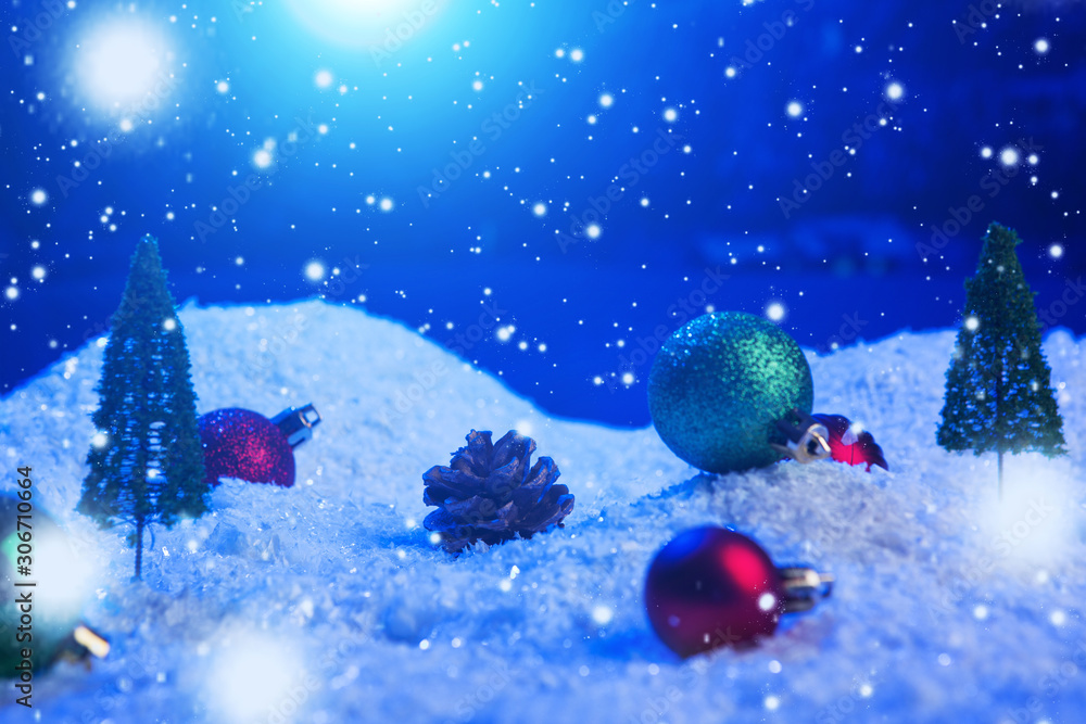 Christmas background with Christmas balls on snow over fir-tree, night sky and moon. Shallow depth of field. Christmas background. Fairy tale. Macro. Artificial magic dreamy world.