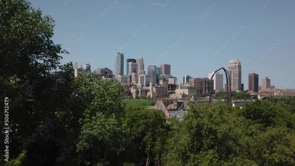 Rising aerial shot through Stone Arch Bridge Park revealing the Minneapolis skyline on a sunny summer day. Rising aerial shot through Stone Arch Bridge Park revealing the Minneapolis skyline on a sunny summer day.
