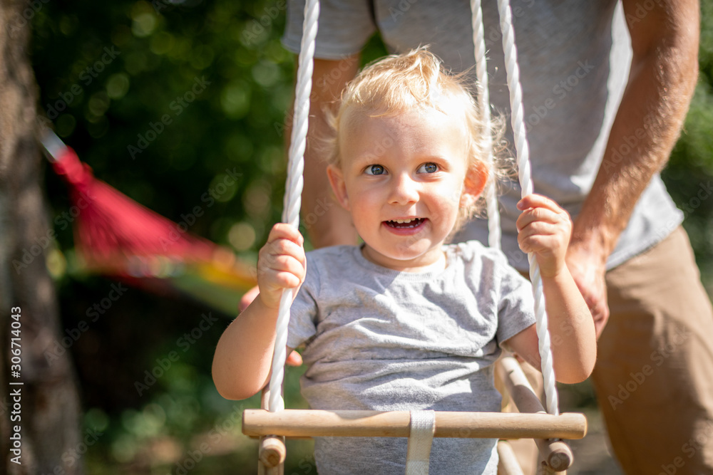 Happy father pushing laughing son on swing in backyard Happy father pushing laughing son on swing in backyard