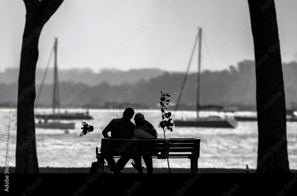 silhouette of a couple sitting on bench at sunset