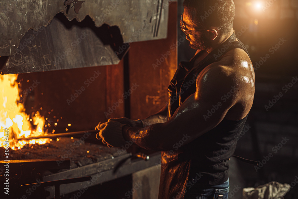handsome blacksmith guy with muscular body, wearing gloves for safety, isolated in workshop handsome blacksmith guy with muscular body, wearing gloves for safety, isolated in workshop