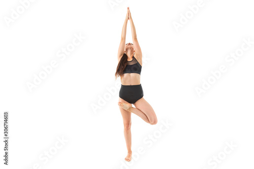 Brunette girl doing yoga in a black sports swimsuit isolated white background
