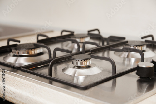The steel gas hob detail on beige wooden surface.