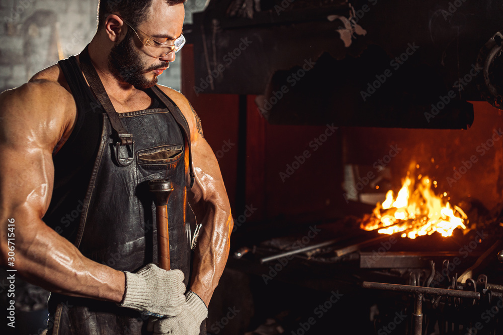 strong powerful muscular man engaged in forging, blacksmithing. handsome attractive bodybuilder worker of workshop, wearing leather apron strong powerful muscular man engaged in forging, blacksmithing. handsome attractive bodybuilder worker of workshop, wearing leather apron
