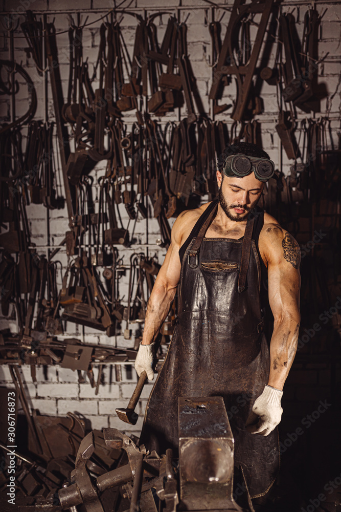 confident forger in leather uniform isolated in workshop. special equipment. strength and power concept. muscular body confident forger in leather uniform isolated in workshop. special equipment. strength and power concept. muscular body