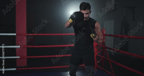 Wallpaper Mural Boxing guy in front of the camera in a dark gym class in the middle of boxing ring Torontodigital.ca