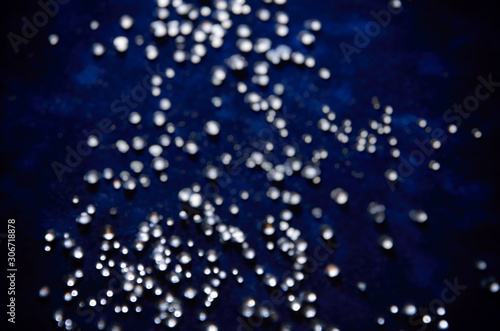 Abstract bokeh pattern of sparkling glass droplets on a dark blue background