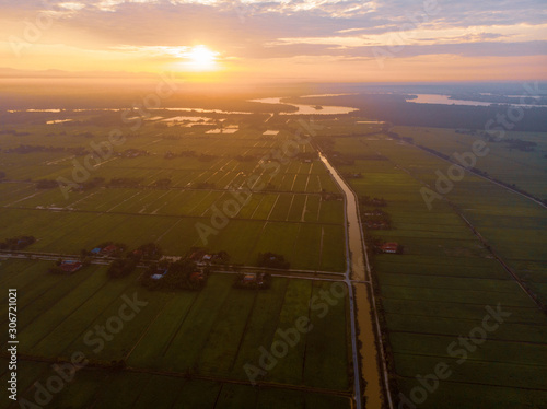 An aerial shot of warming sunrise over the green paddy field. Noise existed in a drone photography.