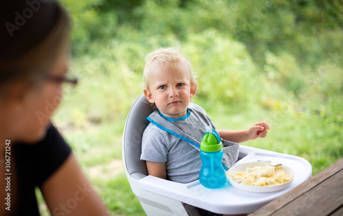 Tableau sur toile Offended and fussy little child boy during eating outdoor