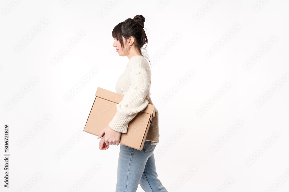 Side view of walking woman holding cardboard with copy space for handwriting in her armpit. Moving day concept. Delivery of online order. Side view of walking woman holding cardboard with copy space for handwriting in her armpit. Moving day concept. Delivery of online order.