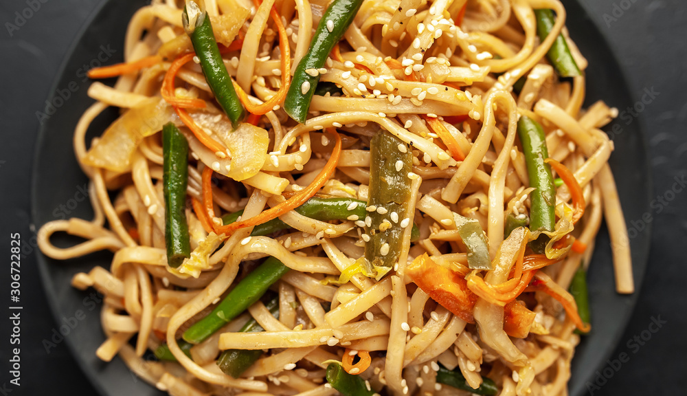 Asian vegetarian food udon noodles with Beijing cabbage, carrots, green beans, bell pepper, onions on a plate on a stone background Asian vegetarian food udon noodles with Beijing cabbage, carrots, green beans, bell pepper, onions on a plate on a stone background