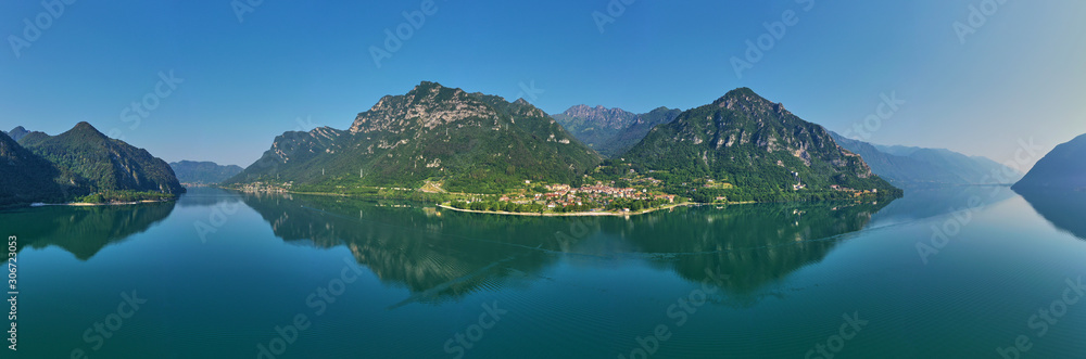 Panoramic view of the mountains and Lake Idro-Lago d'Idro. Autumn season, the reflection in the water of the mountains, trees, blue sky