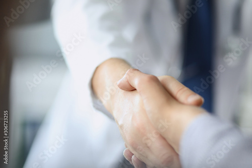 Closeup image of healthcare professional or doctor or dentist shaking hands with patient.