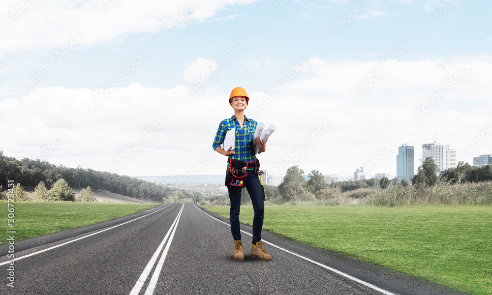 Young woman in safety helmet standing on road Young woman in safety helmet standing on road
