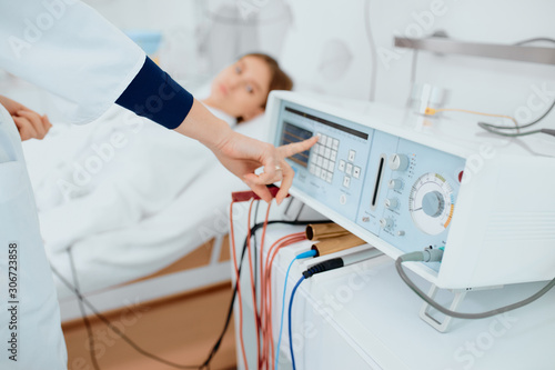 female doctor push buttons on medical equipment while patient lying on bed