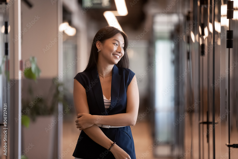 Attractive asian businesswoman standing in modern office hallway