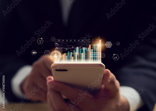 Obraz na plátně Stock exchange market concept, hand trader holding smartphone with graphs analysis candle line on bokeh colors light in night