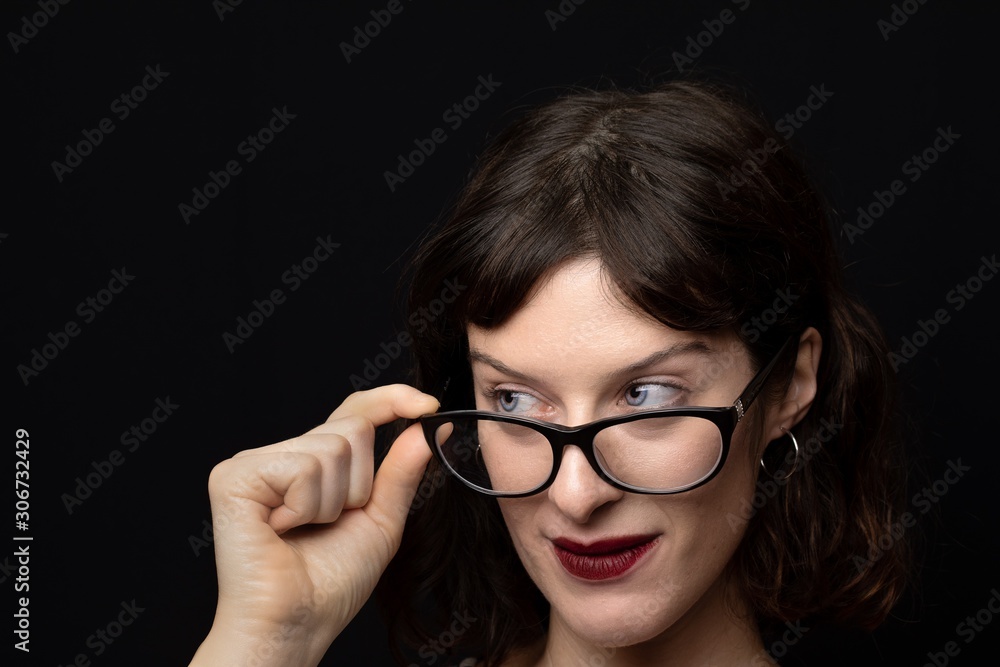 Close-up of a woman with brown hair and blue eyes while resting her glasses on her nose, myopia concept