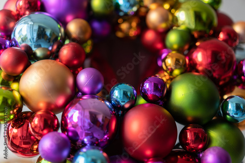 Door decoration with colorful christmas balls at a house door with glass front at daytime. Low angle view, close up.