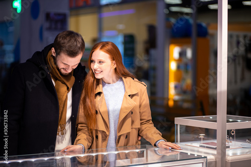 two young beautiful people together choosing, buying golden jewelry for redhaired woman, gift for female © alfa27