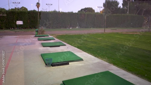 Traveling from a practice area in a golf club, the field is green and with hiber, the shooting mats put in line towards the shooting zone photo