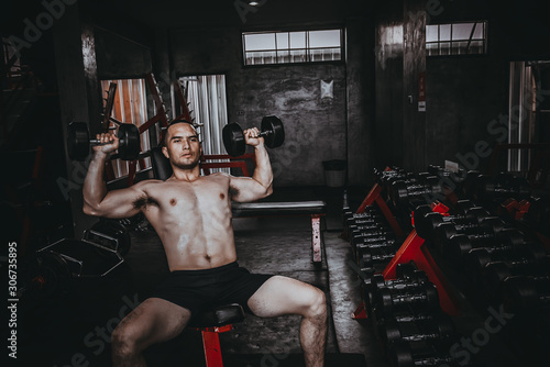 Portrait of asian man big muscle at the gym,Thailand people,Workout for good healthy,Body weight training,Fitness at the gym concept,Prank to abdominal muscles,Lift up dumpbell
