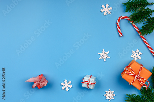 Christmas background. Gift box. Fir branch and cone. Snowflakes. Lollipop. Blue background. Top view. Close-up.