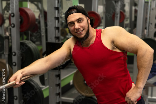 Portrait of a strong, muscular guy in the gym. Happy positive athlete smiling.