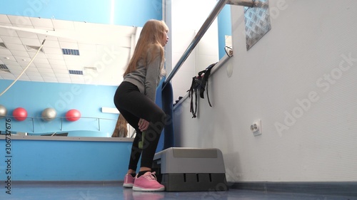 child crouches with dumbbell in hand. training in fitness club. girl strengthens muscles of legs. Fitness club, teenager goes in for sports. Sport lifestyle concept. health promotion in gym.