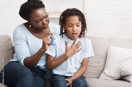 Black mother holding asthma inhaler for daughter photo