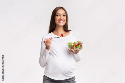 Smiling Pregnant Lady Eating Vegetable Salad Standing, Studio Shot