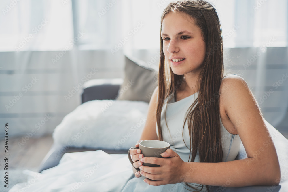portrait of young teenager brunette girl with long hair sitting on sofa with cup at home portrait of young teenager brunette girl with long hair sitting on sofa with cup at home