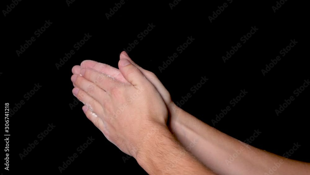 An athlete preparing for workout by chalking and clapping his hands for evenly distributing the chalk powder, isolated on black background. Slow motion. An athlete preparing for workout by chalking and clapping his hands for evenly distributing the chalk powder, isolated on black background. Slow motion.