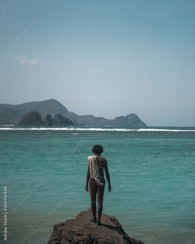 chica afro con toalla posando frente al mar