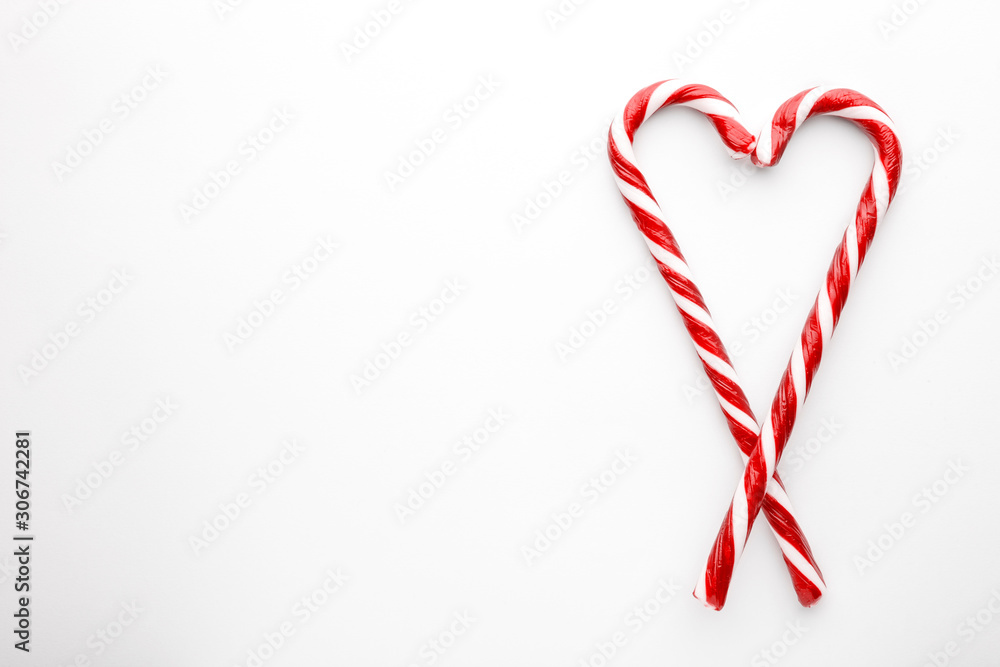 Heart shape made with Christmas candy canes on white background. Minimal composition with peppermint candies. Top view
