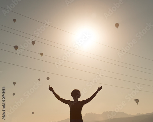 chica viendo globos aerostaticos a la salida del sol photo