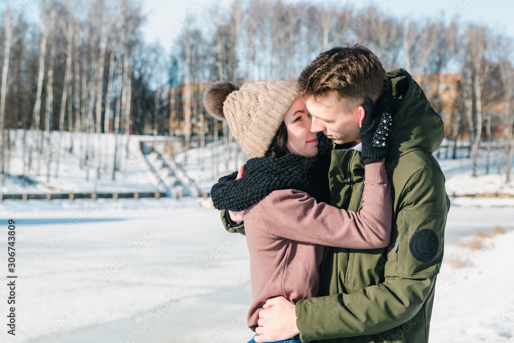 Beautiful young couple in love in a winter park on a clear sunny day. The guy seeks to kiss his beloved girl Beautiful young couple in love in a winter park on a clear sunny day. The guy seeks to kiss his beloved girl