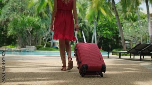 Beautiful traveler woman girl in red dress walking with suitcase at luxury resort, Female tourist woman in tropical hotel near swimming pool. travel tourism vacation happy holiday check-in slow-mo 4 K photo