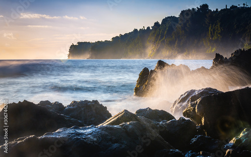 Lava rock shoreline with breaking waves at dawn in Hilo, Hawaii photo