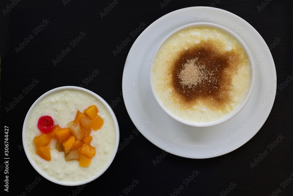 Two bowls of porridge in different flavors stand side by side against a black background and contain fruit or cinnamon with sugar Two bowls of porridge in different flavors stand side by side against a black background and contain fruit or cinnamon with sugar