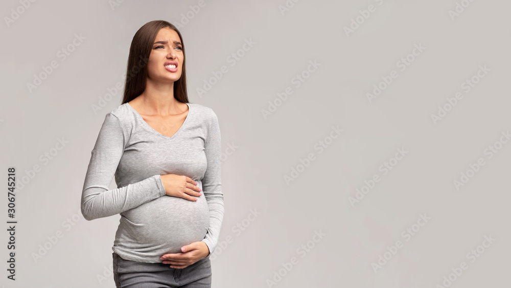 Pregnant Lady Suffering From Abdomen Pain Standing, Gray Background, Panorama Pregnant Lady Suffering From Abdomen Pain Standing, Gray Background, Panorama