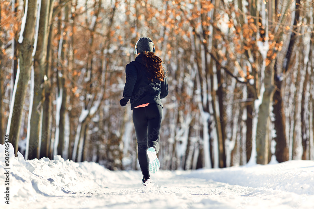 A girl runs through the park in winter