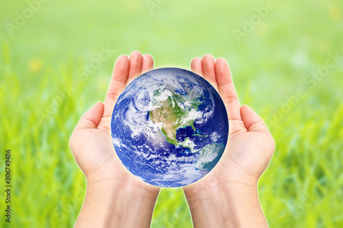 Two hands holding global with grassland background.Elements of this image furnished by NASA