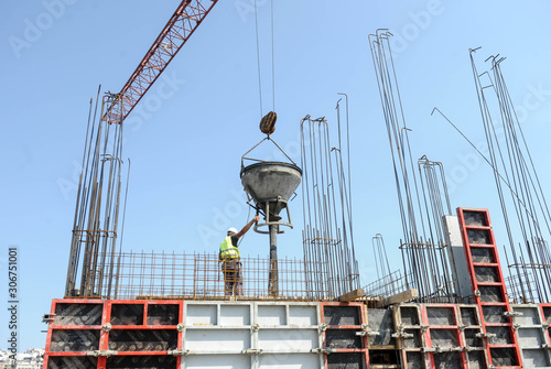 A worker controls concrete bucket used in pouring concrete at construction site
