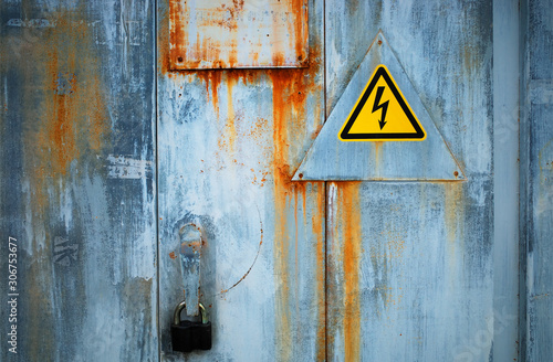 Danger high voltage sign on rusty locked door background