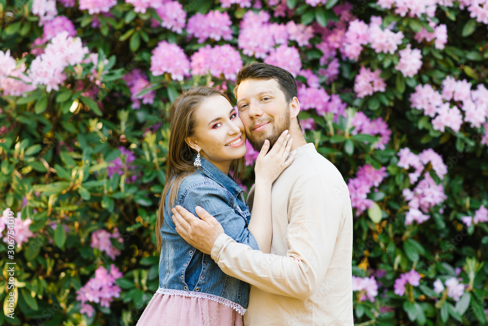 Happy happy young couple in love smiling and enjoying rhododendron bloom in spring. Valentine's day Happy happy young couple in love smiling and enjoying rhododendron bloom in spring. Valentine's day
