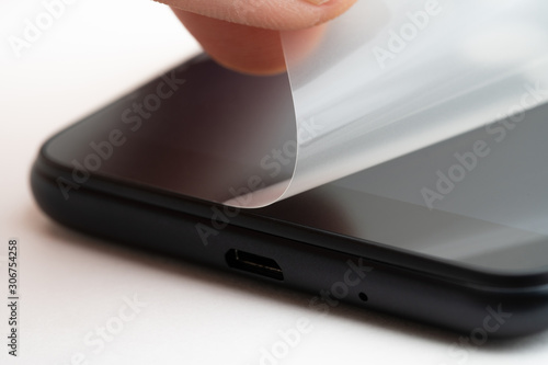 Fotografia Man removing protective film from new smartphone